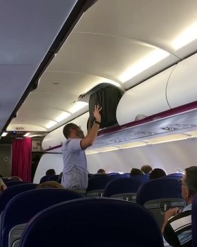 Un passager veut ranger sa valise dans un avion