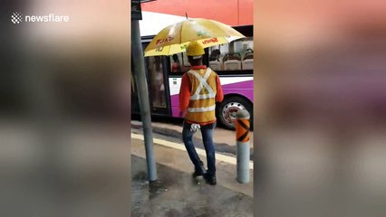 Kind-hearted builders shelter commuters with umbrellas during rain storm