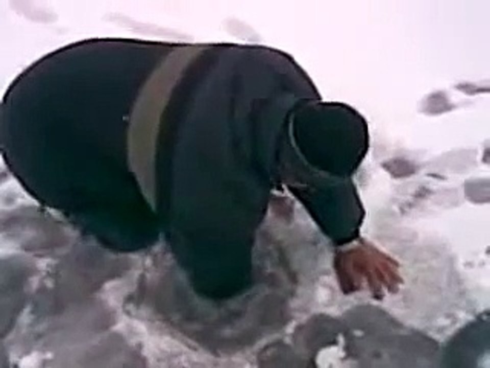 Russian man catches a big fish with bare hands from an ice hole