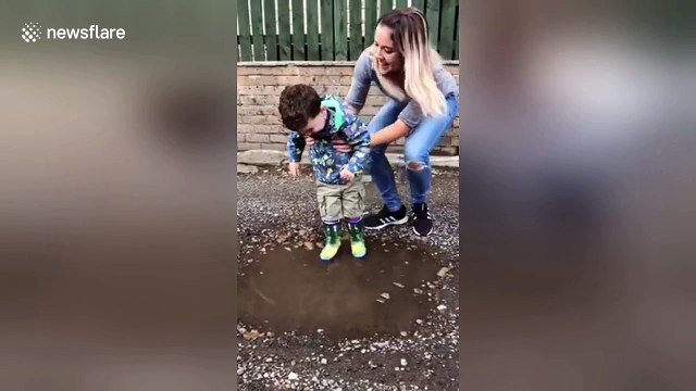 Boy with Cerebral palsy, laughs with joy as he splashes in puddle for the first time