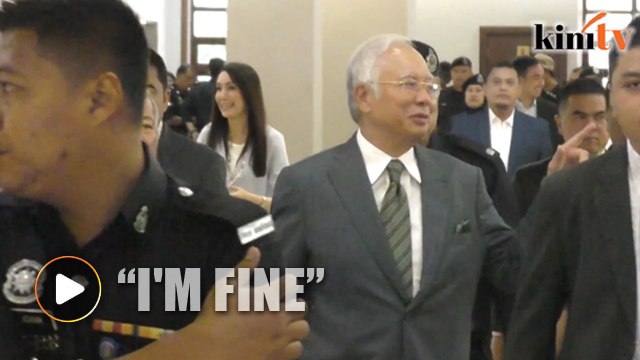 Najib smiles as he's escorted by over a dozen cops