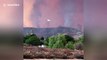 Firefighting plane drop trail of bright red retardant against apocalyptic sky