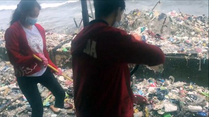 Des volontaires tentent de stopper les dechets portés par la mer dans les Philippines