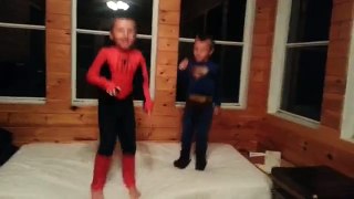 Superman and Spiderman jumping on a bed
