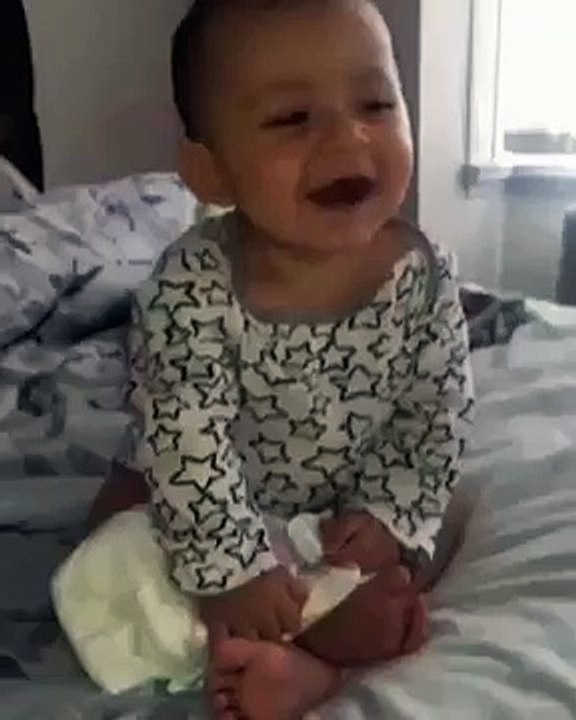 baby falls to its side on the bed as he laughs