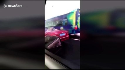 Man holds umbrella while driving convertible in rain