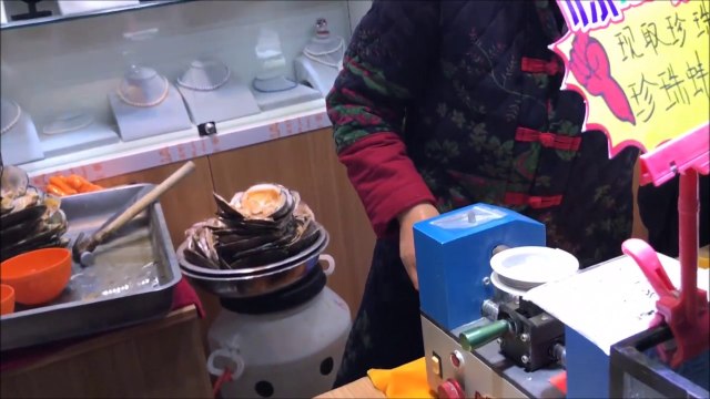 Elle ouvre une huître perlière en chine et en sort plusieurs perles