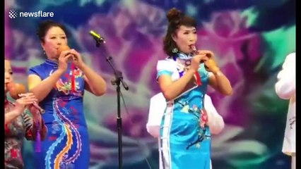 Woman plays traditional Chinese flute from the wrong end