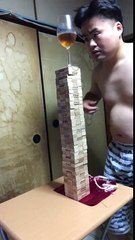 Il enlève une nappe sous une pile de Jenga sans faire tomber un verre de vin