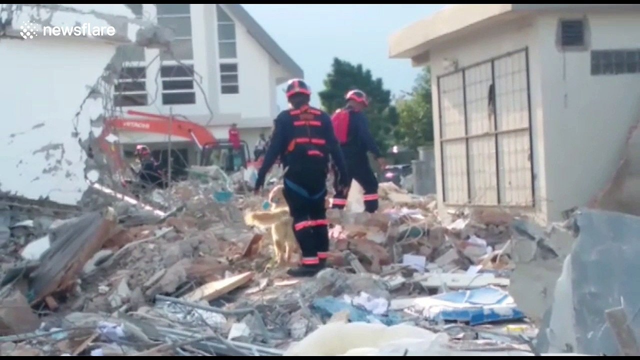 Workers remove body bags as rescue operations at Palu hotel continue