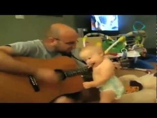 Bebé se divierte bailando mientras su papá toca la guitarra