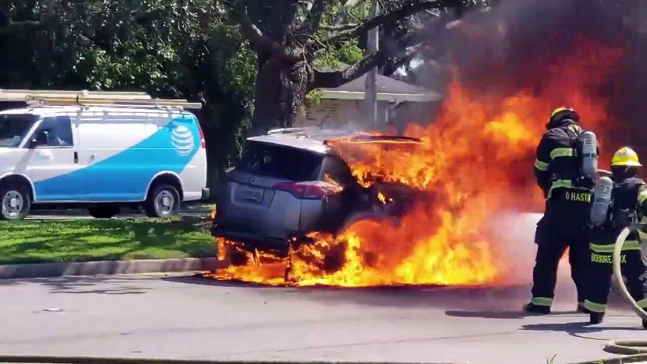 Un pompier tente d'éteindre une voiture en feu...