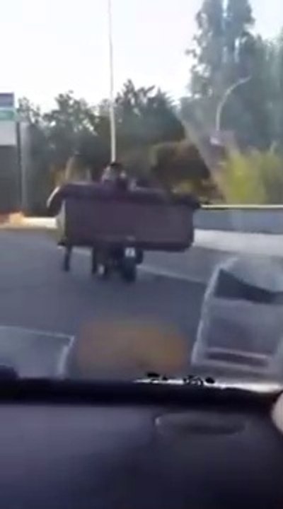 En scooter sur le périphérique parisien, il transporte un canapé avec 2 amis assis dessus