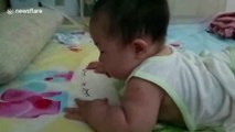 Cute baby tries to eat strawberry pattern on bed sheet