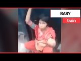 Mum cradles baby while sat between two speeding train carriages | SWNS TV