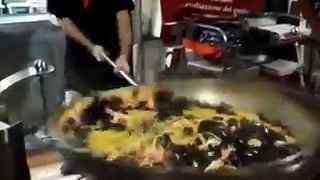 Chef handling an enormous frying pan   