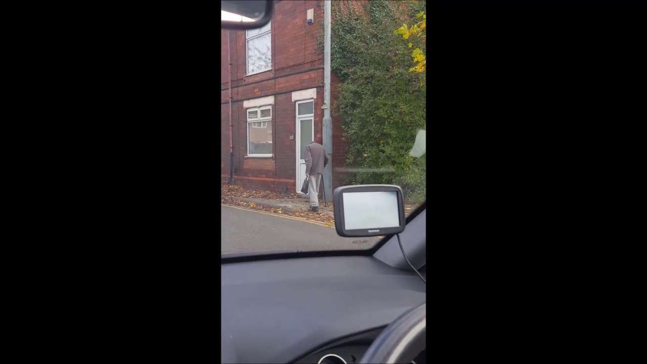 Une femme filme un homme sans tête en train de marcher dans la rue.