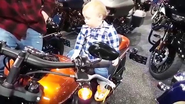 La réaction d'un petit garçon assis sur une moto