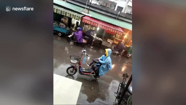 Small boy keeps his mum's bike seat dry in the rain with his own body
