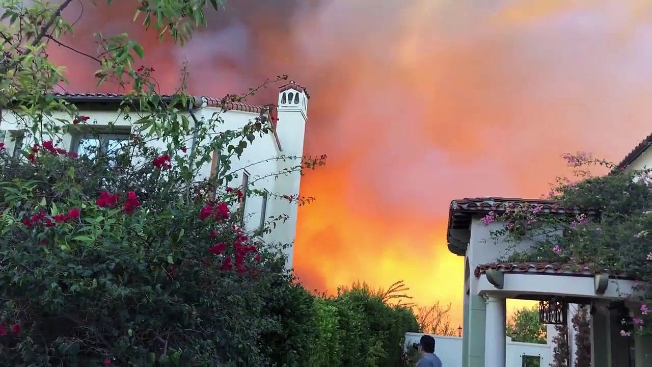 Un avion largue du retardant sur un feu de maison
