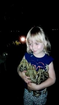 Une fillette se balade avec des grenouilles géantes dans les bras