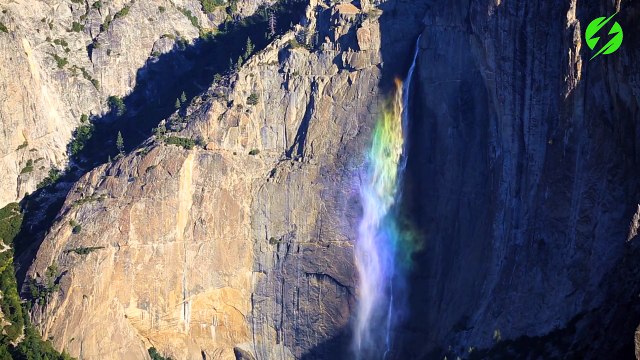 Un magnifique arc-en-ciel se crée sur une chute d'eau en montagne
