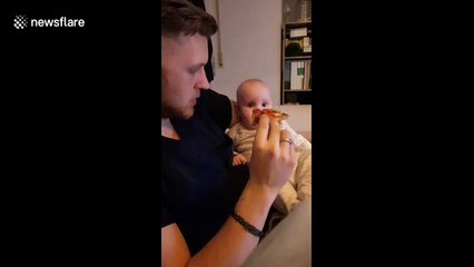 Baby fascinated by father eating a pizza