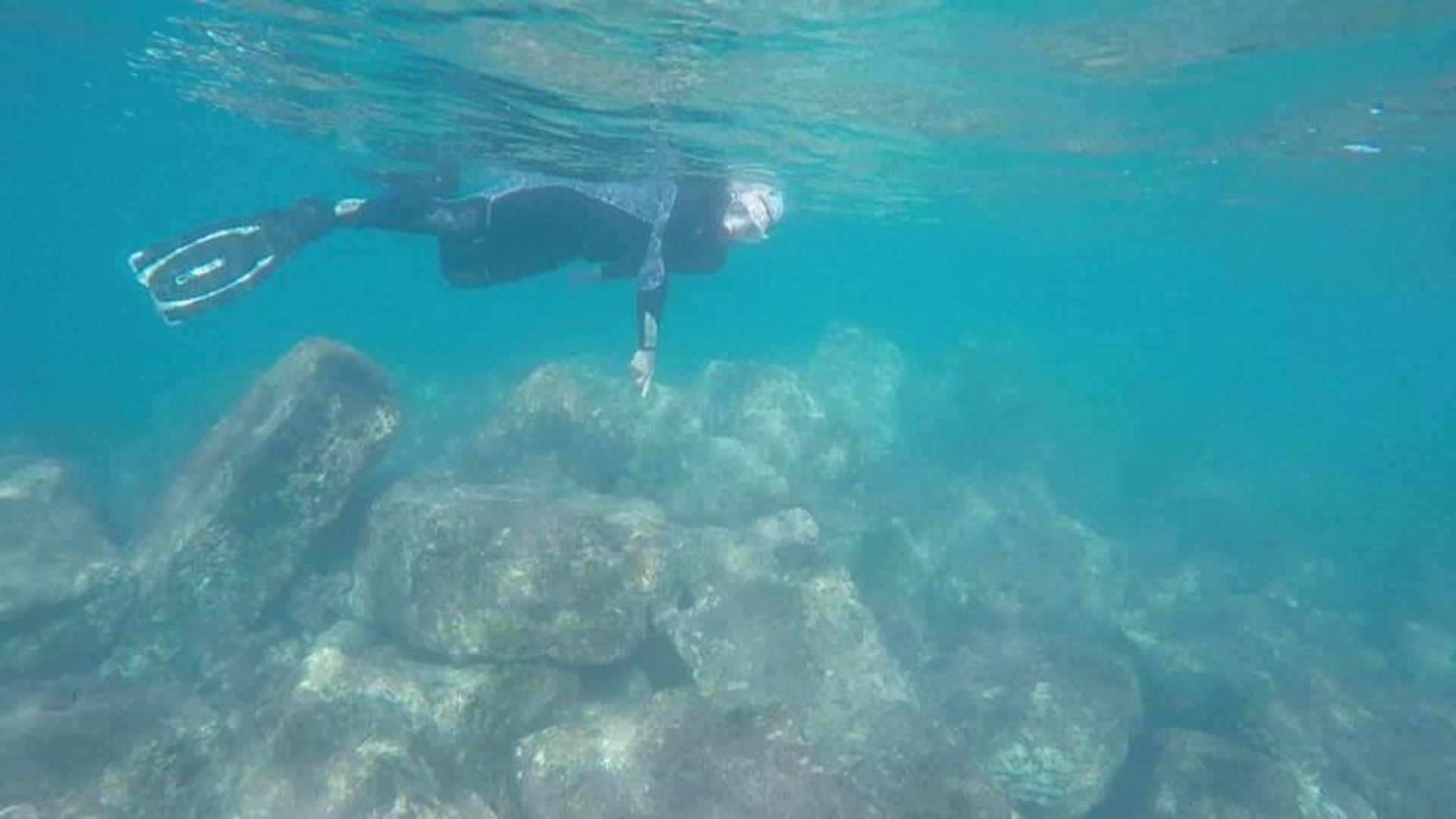 ⁣Divers glide over ruins at underwater archaeological site