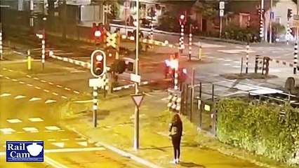 Un homme en scooter regarde une fille dans la rue et se prend la barrière du passage à niveau