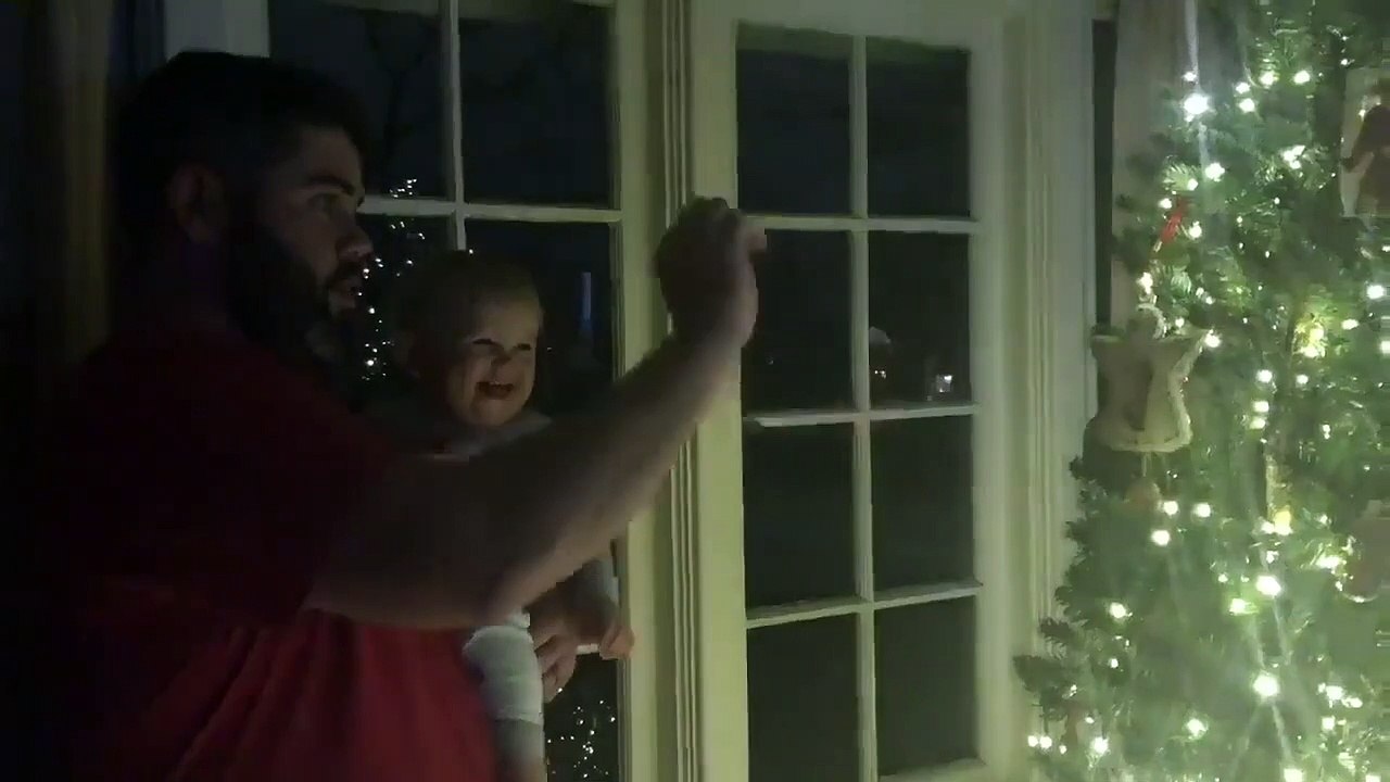 Un bébé rigole quand papa allume le sapin de noël