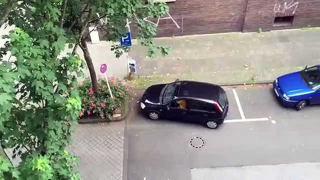 Une femme au volant dune petite voiture essaie de faire un créneau