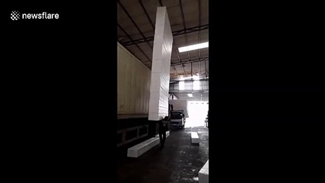 Worker lifts up and balances tower of 18 foam blocks