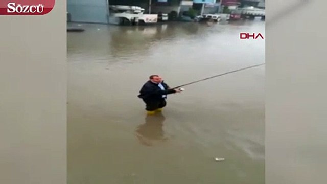 Su taşkınında oltayla balık tutmaya çalıştı