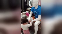 Adorable moment polite toddler greets mannequins inside shopping mall