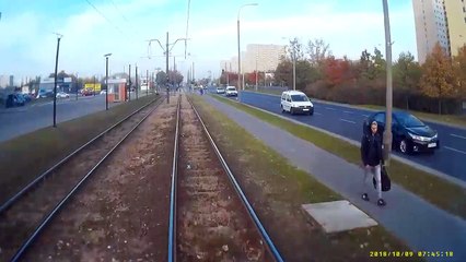 Une femme traverse une voie ferrée le casque sur les oreilles