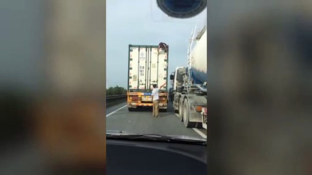Une femme se cache sur le toit d'un camion qui roule sur une autoroute