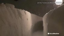 With roads impassable, ski resort guests travel between towering walls of snow