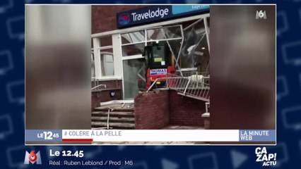 Un ouvrier en colère fonce dans le hall d'un hôtel avec une pelleteuse