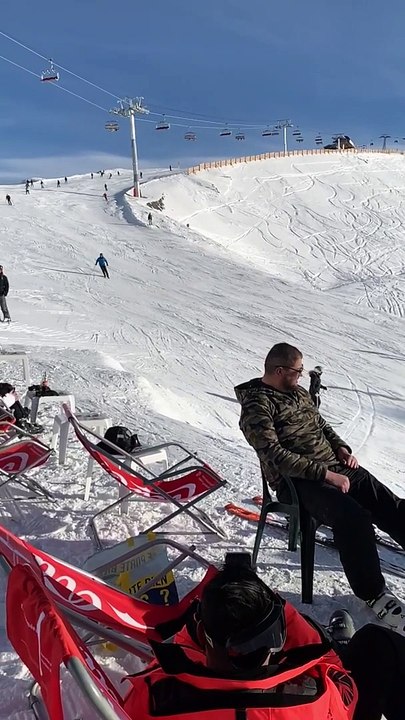 Backflip en ski au-dessus des touristes dans les transats sur la piste de ski