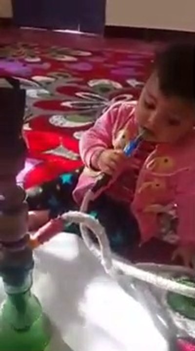 Un papa laisse sa petite fille fumer la chicha.