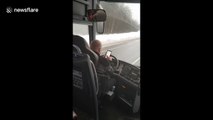 Bus driver types messages with both hands while driving on icy road