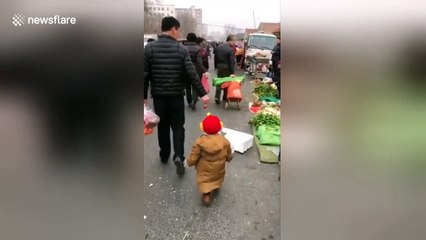 Smart dad uses strawberry to encourage son to follow him through market