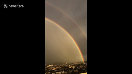 Spectacular double rainbow arcs over Los Angeles cityscape