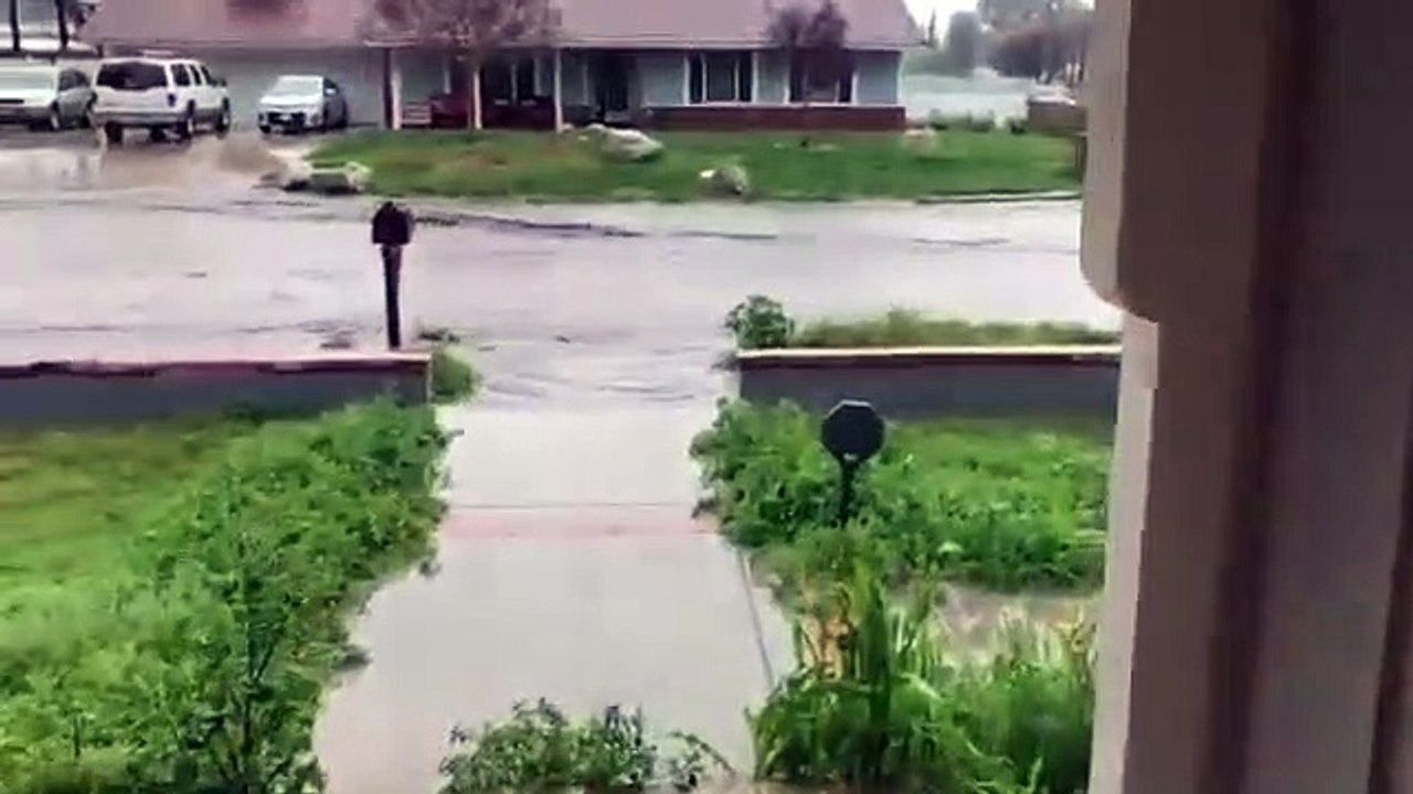 Un homme fait de la bouée flamant rose dans une route inondée