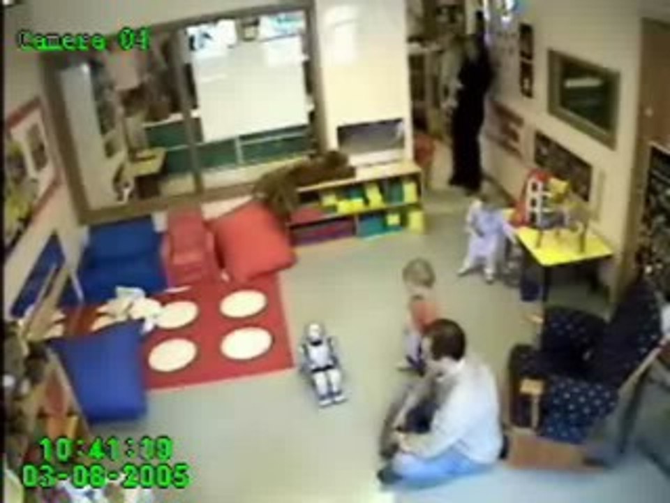 Una niña mira a QRIO mientras abraza a un muñeco