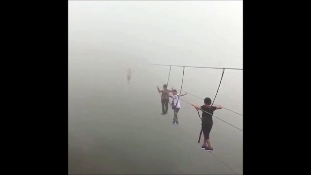 Ces touristes traversent un pont suspendu perdu dans la brume... Impressionnant
