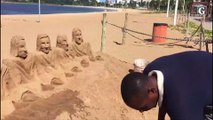 Homem faz escultura de areia na Praia de Camburi