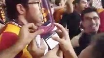 Un supporter du Galatasaray fait tomber son téléphone et le remonte à l'aide de plusieurs écharpes