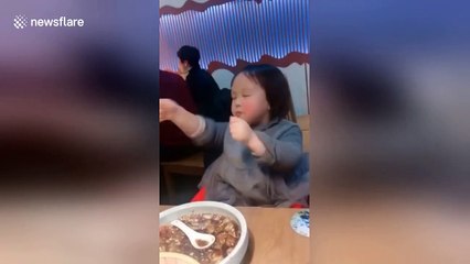 Excited girl dances after having her favourite soup in restaurant in Shanghai