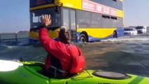 Faire du kayak sur une route inondée alors que des voitures roulent encore